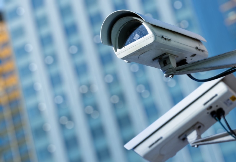 Image of a CCTV camera outside within a city centre, with a large office building in the background